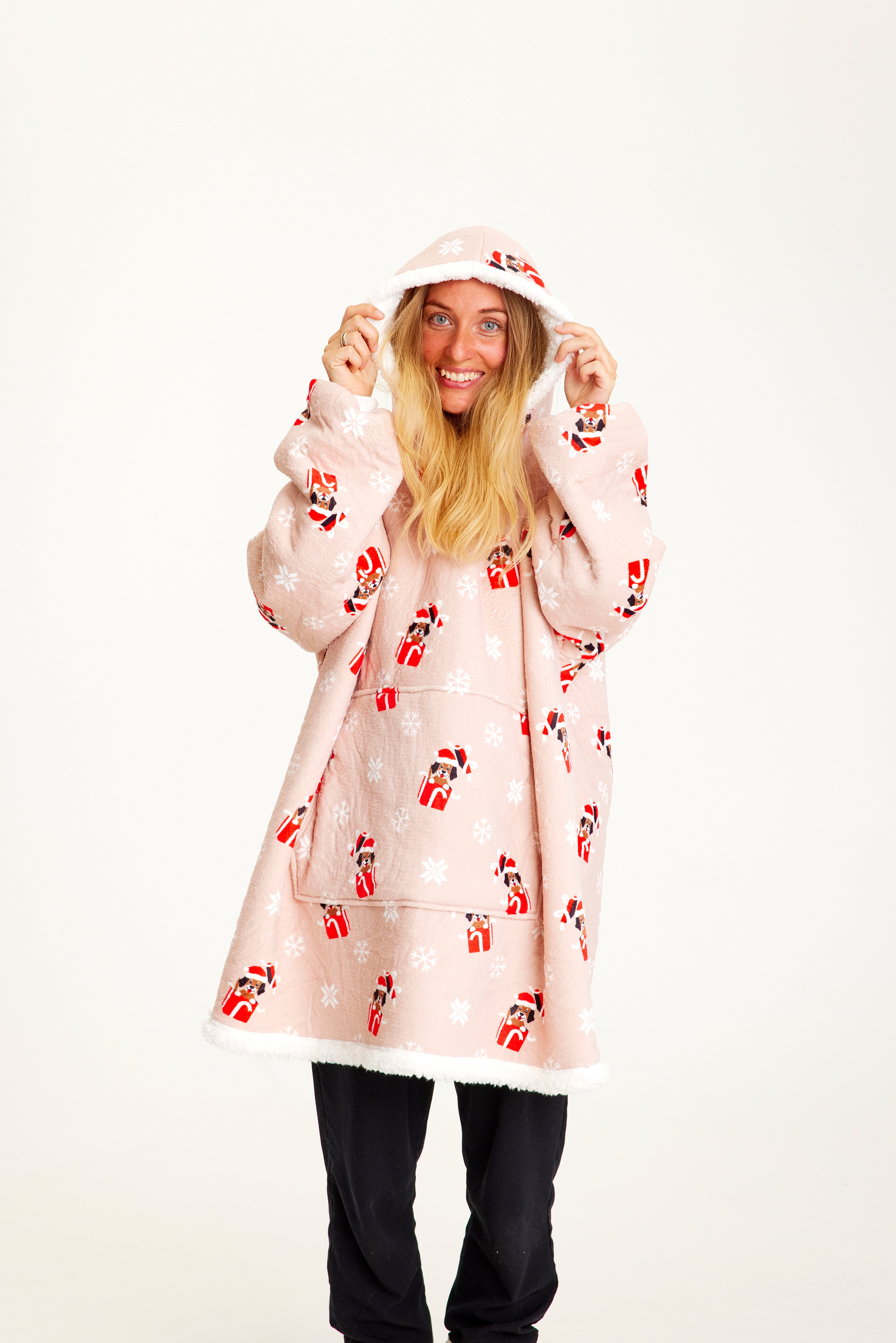 Une femme posant avec un sweat à capuche de Noël rose avec des chiens.